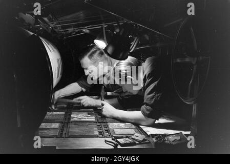 Zwei Drucker Lettern setzen zu einem von Rotationsdruckmaschine Schriftstatz un zusammen, Deutschland 1930er Jahre. Deux imprimantes sont l'organisation de type métal sortes sur une presse rotative, Allemagne 1930. Banque D'Images