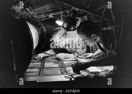 Zwei Drucker Lettern setzen zu einem von Rotationsdruckmaschine Schriftstatz un zusammen, Deutschland 1930er Jahre. Deux imprimantes sont l'organisation de type métal sortes sur une presse rotative, Allemagne 1930. Banque D'Images