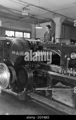 Eine Druckereimitarbeiterin Papierbögen bedruckten high die eine dans Planschneidemaschine Maschinenbaukonzern, produziert vom MAN (Maschinenfabrik Augsburg-Nürnberg), Deutschland 1930 er Jahre. Un travailleur dans une imprimerie met le papier imprimé à l'intérieur d'une machine à couper les feuilles, qui est produite par la société d'ingénierie mécanique (homme), Maschinenfabrik Augsburg-Nürnberg Allemagne 1930. Banque D'Images