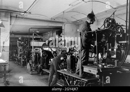 Druckereimitarbeiter bei der Arbeit an der Rotationsdruckmaschine Maschinenbaukonzerns in den Werken des MAN (Maschinenfabrik Augsburg-Nürnberg), Deutschland 1930 er Jahre. Les travailleurs de l'imprimerie sur la presse d'impression rotative dans les usines de la société d'ingénierie mécanique (homme), Maschinenfabrik Augsburg-Nürnberg Allemagne 1930. Banque D'Images