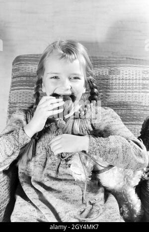 Ein Mädchen isst Liegnitzer Bomben, Deutsches Reich 1930er Jahre. Un girl eating Liegnitzer Bomben, Allemagne 1930. Banque D'Images