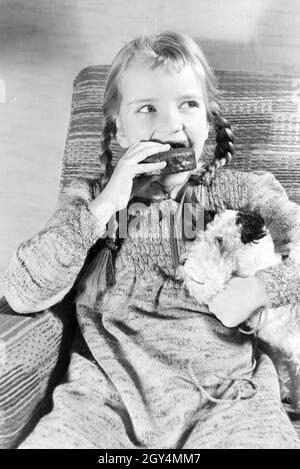 Ein Mädchen isst Liegnitzer Bomben, Deutsches Reich 1930er Jahre. Un girl eating Liegnitzer Bomben, Allemagne 1930. Banque D'Images