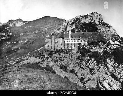 De nombreux randonneurs de montagne s'assoient sur des bancs ou dans l'herbe au soleil, en face du Rotwandhaus, dans les montagnes Schliersee.La cabane a été ouverte en 1907.Photo non datée, prise vers 1910.[traduction automatique] Banque D'Images