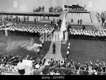 Un grand drapeau olympique a été hissé à l'ouverture des Jeux Olympiques d'aviron, qui ont eu lieu entre le 11 et le 14 août au cours de régate de Grünau près de Berlin.Des spectateurs dans les tribunes ainsi que des journalistes et des policiers ont montré le salut d'Hitler.Les compétitions de canoë ont eu lieu sur le même cours déjà à partir d'août 7, donc la photo aurait pu être prise le 7 août.[traduction automatique] Banque D'Images