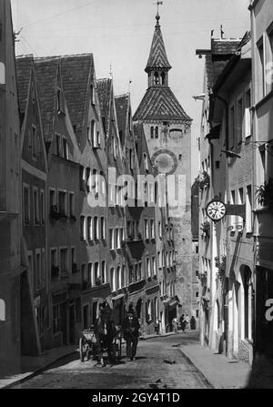 Un cheval se bat sur l'Alte Bergstraße à Landsberg am Lech.Le coachman, habillé en costume traditionnel fin, marche le long.Sur la droite se trouve la boutique d'un opticien.A l'extrémité inférieure de la rue, le chemin traverse le Schmalzturm pour rejoindre la partie la plus ancienne de la ville.Photo non datée, probablement prise autour de 1935.[traduction automatique] Banque D'Images