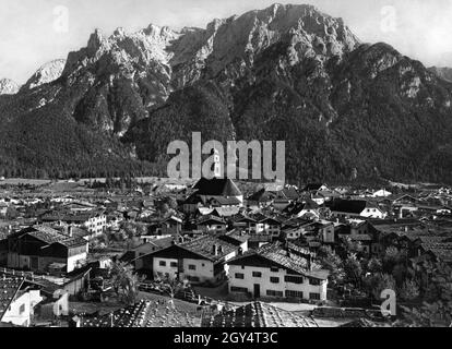 Cette photo, prise vers 1930, montre Mittenwald avec l'église Saint-Pierre et Paul au centre.Derrière le village se dresse la gamme de Karwendel du Nord avec Karwendelkopf, Karwendelspitze et Linderspitze.[traduction automatique] Banque D'Images