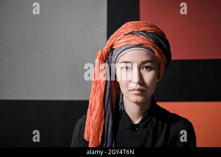 Portrait d'une jeune belle femme en vêtements musulmans regardant l'appareil photo contre le mur coloré Banque D'Images
