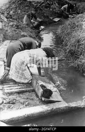 Dans un camp de réfugiés, les femmes lavent leurs vêtements par un ruisseau.[traduction automatique] Banque D'Images