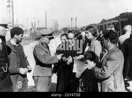 Une fois évacués par le gouvernement français, les alsaciens et les résidents de Lorraine sont maintenant transportés vers la région annexée par les Allemands.Sur la photo : à la gare de Saint-Diziers, un soldat de Wehrmacht vérifie les passeports des réfugiés qui sont arrivés.[traduction automatique] Banque D'Images