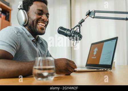 Black man dans le casque d'enregistrement de podcast et rire Banque D'Images