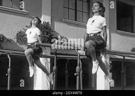 'Au début du mois de juillet 1939, plusieurs jeunes femmes de toutes les régions d'Italie sont venues à Rome pour rejoindre la ''Giovani Fasciste'', une branche du fasciste Gioventu Italiana del Littorio.Les 1200 femmes invitées devaient apprendre dans différents contenus de cours pour les chefs de groupe (Capo centuria).La photo, prise le 6 juillet 1939, montre deux femmes faisant de la gymnastique sur les barres parallèles.Le cours de début juillet portait sur le sport et l'entraînement.[traduction automatique]' Banque D'Images