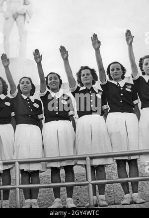 «les filles et les jeunes femmes, âgées de 16 à 20 ans, qui ont grandi avec le fascisme, lèvent leurs bras dans le salut romain.Ils sont dans le stade en marbre du Foro Mussolini (aujourd'hui Foro Italico) et appartiennent au fasciste ''Opera nazionale del dopolavoro' (OND).La photographie a été prise en 1938.[traduction automatique]' Banque D'Images