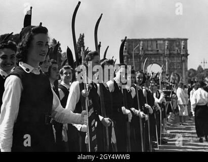 Les filles appartenant à la Giovani Italiane au sein de l'organisation fasciste de jeunesse Gioventu Italiana del Littorio (GIL) se tiennent dans leur section sur la via Trionfale (maintenant via di San Gregorio) à Rome.Ils participent à une parade des jeunes fascistes en 1939.Le groupe de filles est la section de ski du GIL de Turin.L'Arc de Constantine peut être vu en arrière-plan.[traduction automatique] Banque D'Images