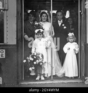 Le 10 novembre 1941, un mariage a eu lieu à Milan où la mariée, la fête de mariage et le prêtre sont arrivés à l'église par tram.En raison des restrictions de la guerre, c'était la seule façon de se rendre à l'église où le mariage a eu lieu.La photo montre la mariée et le marié à l'entrée ouverte du tram.Devant eux se trouvent un enfant de fleurs et une fille tenant le train.[traduction automatique] Banque D'Images