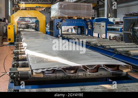 Convoyeur avec produits emballés finis en carreaux de métal pour le toit dans l'atelier d'usine de travail des métaux. Banque D'Images