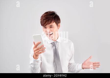 Beau jeune homme asiatique d'être surpris après avoir lu un message de smarrtphone Banque D'Images