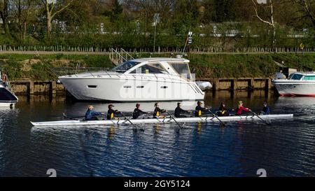 Adolescents en bateau (aviron 8 sur la séance d'entraînement, apprentissage de la rangée) passant des bateaux sur les quais - Sunny River Ouse, North Yorkshire, Angleterre Royaume-Uni. Banque D'Images