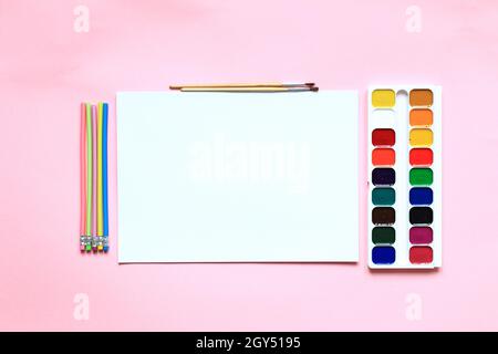 Un ensemble de peintures et de crayons pour dessiner sur fond rose. Papeterie pour l'école. Disposition des produits pour l'artiste. Vue de dessus. Banque D'Images