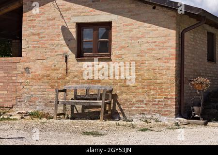Un ancien banc en bois sous une fenêtre en bois d'une ferme en pierre dans la campagne italienne (Toscane, Italie, Europe) Banque D'Images