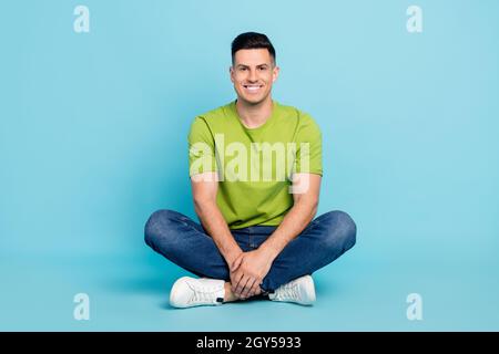 Pleine longueur corps photo homme décontracté vêtements assis sourire isolé pastel bleu couleur fond Banque D'Images