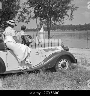 Für den Werbefoto Personenkraftwagen Ford Eifel mit einem Paar über einen Fluß schauend, Deutschland 1935. Photo commerciale pour le passager car Ford Eifel avec couple watching sur une rivière, Allemagne 1935. Banque D'Images