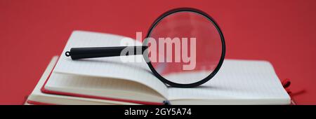 Loupe sur pile de livres sur fond rouge Banque D'Images
