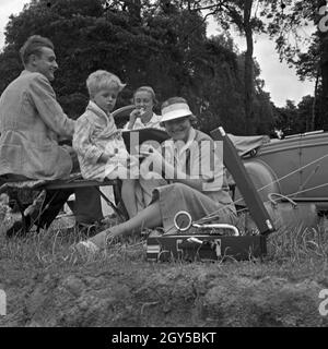 Ein Mann, zwei Frauen und ein kleiner Junge sitzen vor einem une Klapptisch einem Zelt, Deutschland 1930er Jahre. Un homme, un petit garçon et deux femmes assises à une table pliante en face d'une tente, Allemagne 1930. Banque D'Images