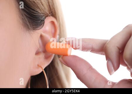 Femme insère des bouchons d'oreille orange doux dans le contour d'oreille Banque D'Images