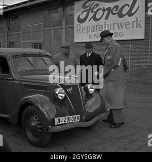 Fachgespräche mit dem Mechaniker am Motor Ford von Eifel, Deutschland 1930 er Jahre. Discussion d'experts avec le garage manager à la serrure d'une Ford Eifel, Allemagne 1930. Banque D'Images
