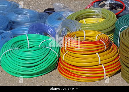 Équipement de jardin pile de tuyaux d'eau en plastique coloré sur le marché sol Banque D'Images