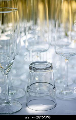 Gros plan de différents verres, verres à champagne et verre à cocktail sur une table avec nappe blanche, accent sur le verre à cocktail Banque D'Images