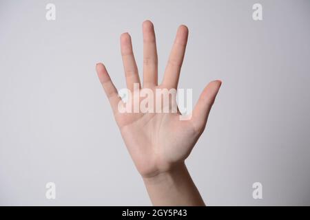 Main femelle étendue dans le salut isolé sur blanc. Numéro cinq. Banque D'Images