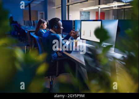 Deux directeurs travaillent dans le bureau de nuit, vue arrière.Hommes et femmes travailleurs, centre d'affaires sombre à l'intérieur sur fond, lieu de travail moderne Banque D'Images