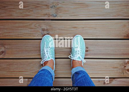Jambes pour Femme en Sneakers vertes menthe sur la terrasse avec espace de copie. Vue de dessus et point de vue personnel Banque D'Images
