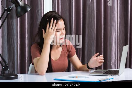 Travail à domicile, fatigués ou fatigués entreprise asiatique jeune belle femme assise sur un bureau espace de travail fatigue effort main tenir la tête après de longues années de service Banque D'Images