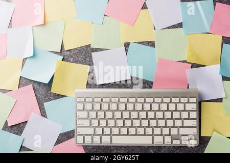 Au-dessus de nombreuses notes vierges bâton de papier avec le clavier moderne d'ordinateur sur fond concret, le concept de mémoire de rappel d'affaires aujourd'hui Banque D'Images