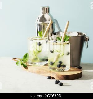 Boissons d'été tendance avec concombre, menthe et myrtille sur fond bleu ciel Banque D'Images