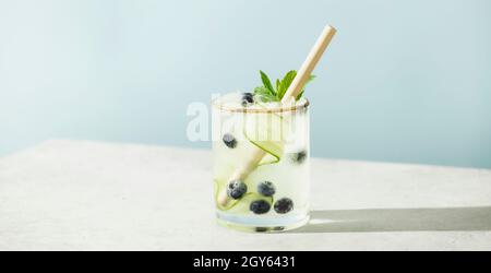 Boissons d'été tendance avec concombre, menthe et myrtille sur fond bleu ciel Banque D'Images