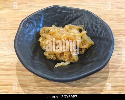 Salade de méduses dans une assiette noire sur la table en bois. Banque D'Images