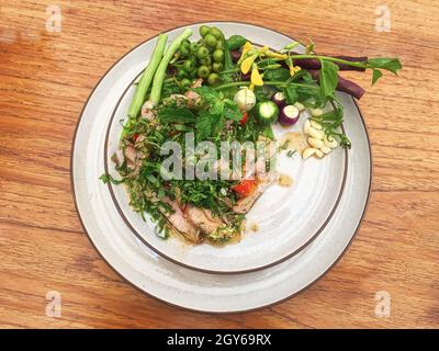 Thai Salade de porc grillé ou Nam Tok Moo dans la plaque sur la table en bois. Banque D'Images