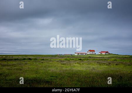 Hafnarfjordur, Islande - 17 juillet 2021 : un paysage de campagne islandaise.Petite église avec toit rouge à l'horizon.Champs d'herbe verte, verc Banque D'Images