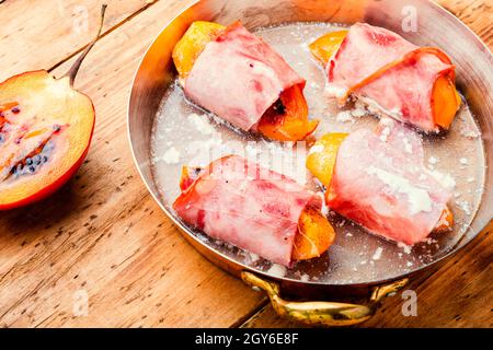 Morceaux de Tamarillo emballés et cuits avec du jambon et du bacon Banque D'Images