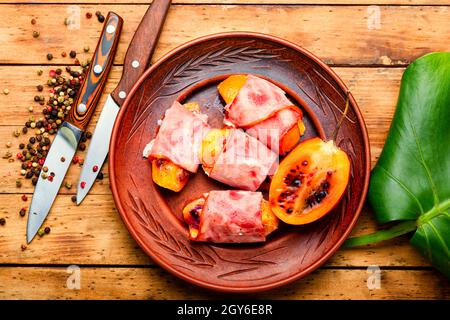 Morceaux de Tamarillo emballés et cuits avec du jambon et du bacon Banque D'Images