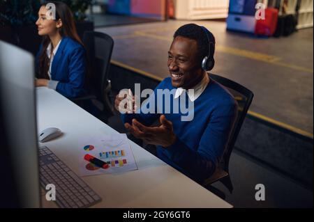 Deux managers souriants travaillent dans le bureau de nuit.Les hommes et les femmes sont gais, le centre d'affaires est sombre et l'intérieur est en arrière-plan, le lieu de travail est moderne Banque D'Images