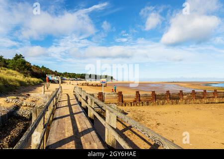 Promenade menant à des cabanes de plage et de plage donnant sur la baie de Holkham à Well-Next-the-Sea dans un matin lumineux et ensoleillé d'octobre Banque D'Images