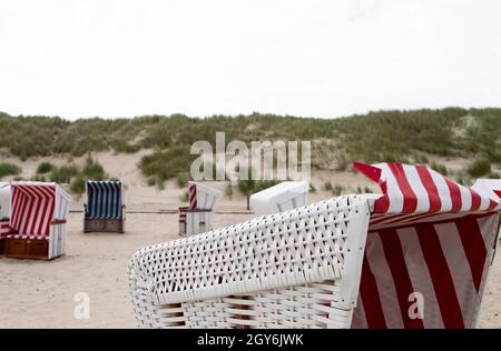 La photo montre quelques chaises de plage sur l'île de Baltrum de la mer du Nord avec ciel nuageux Banque D'Images