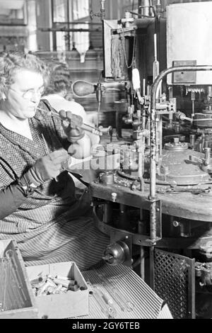 Eine/bei der Produktion von Leuchtröhren, Deutschland 1930 er Jahre. Une femme memmber produisant des tubes fluorescents, Allemagne 1930. Banque D'Images