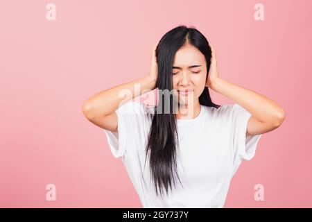 Portrait asiatique beau mignon jeune femme ont des oreilles fermées avec les paumes de la main et les yeux fermés, studio tourné isolé sur fond rose, des couvertures thaïlandaises de femme Banque D'Images