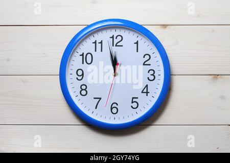 Horloge murale bleue avec minuit nouvel an sur fond en bois Banque D'Images