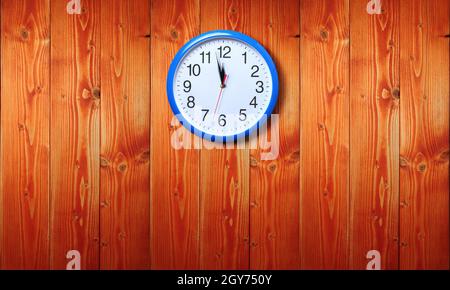 Horloge murale bleue avec minuit nouvel an sur fond en bois Banque D'Images